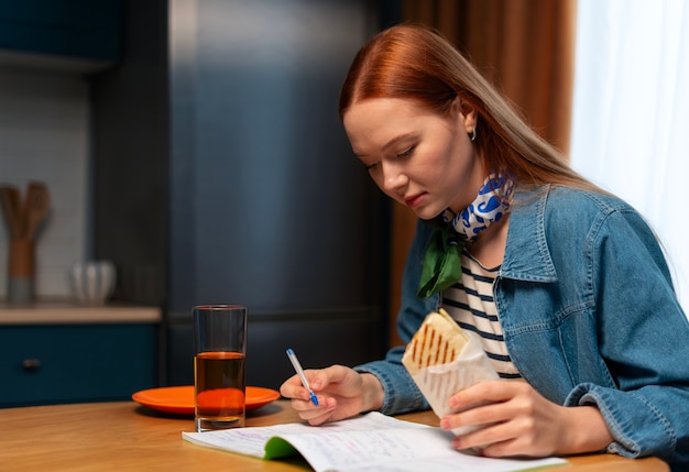 Medium shot woman with  paper-wrapped sandwich