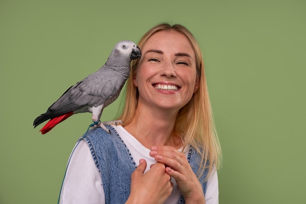 Medium shot woman with parrot in studio