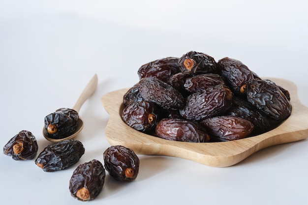 Medjool dates in a container on a white background It is a fruit that Muslims eat during the fasting