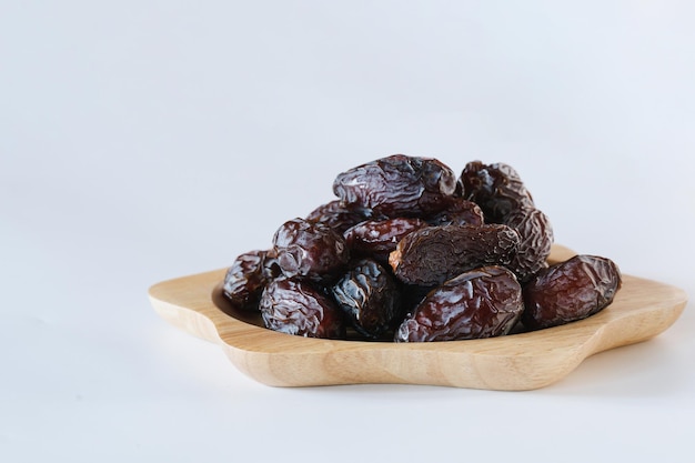 Medjool dates in a wooden plate on a white background It is a wonderful fruit.