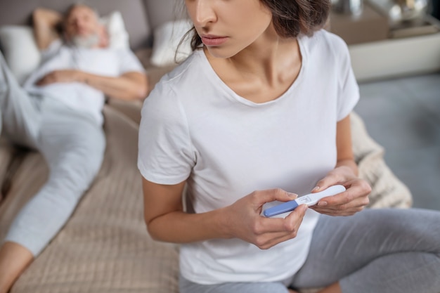 Meeting epectations. A young woman holding her positive pregnancy test