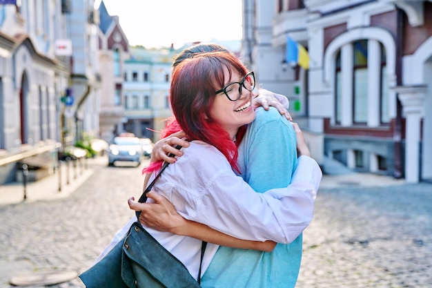 Meeting hugging teenage male and female friends on the city street