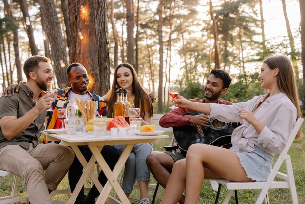 Meeting of multiracial group of friends playing guitar singing eating dinner and drinking wine