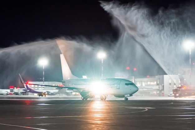 Meeting a new aircraft at a night airport the tradition of wash spray pouring water from fire trucks