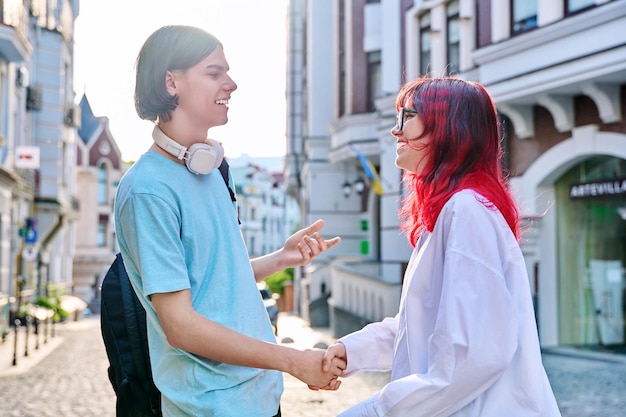 Meeting shaking hands teenage male and female friends on the city street