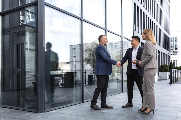 Meeting of three successful business people diverse dream team man and woman outside office building