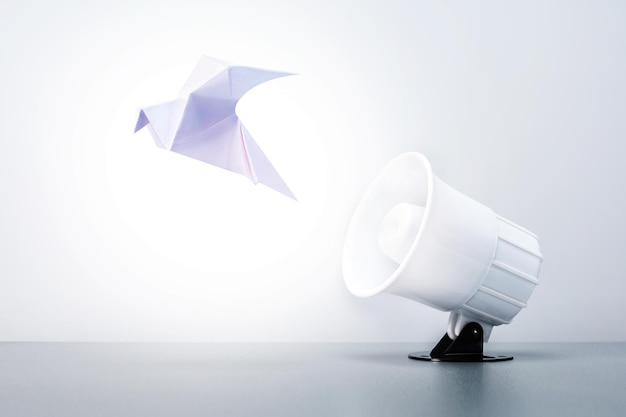 Megaphone with paper dove on grey background Concept of peace free speech