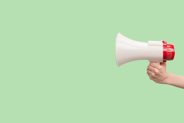 Megaphone in woman hands on a green background