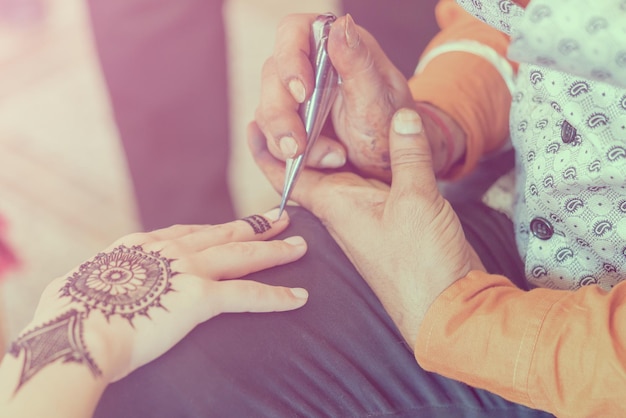 Mehendi Woman draws on hand a beautiful pattern Toned