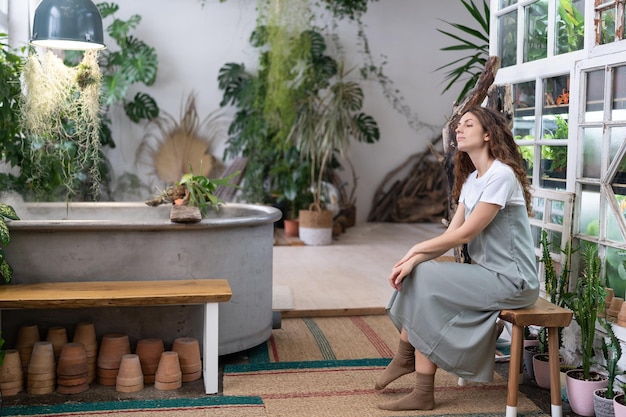 Melancholic gardener female resting after work in floral store or greenhouse Mental health concept