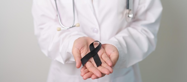 Melanoma and skin cancer Vaccine injury awareness month and rest in peace concepts doctor holding black Ribbon