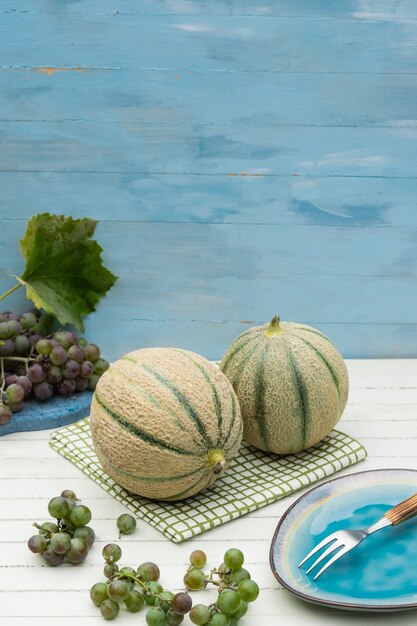 Melon cantaloupe on a wooden background Green melon and ripe grapes selective focus