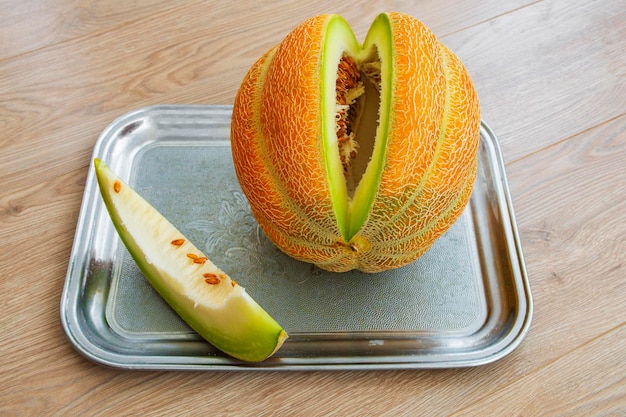 The melon is lying on a tray a slice has been cut off from it