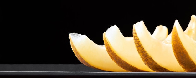 Melon slices on a wooden board on a dark background with copy space