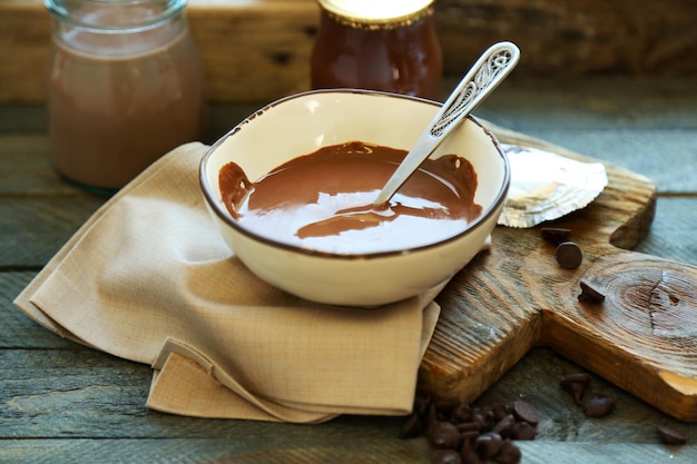 Melted chocolate in glass bowl on wooden background