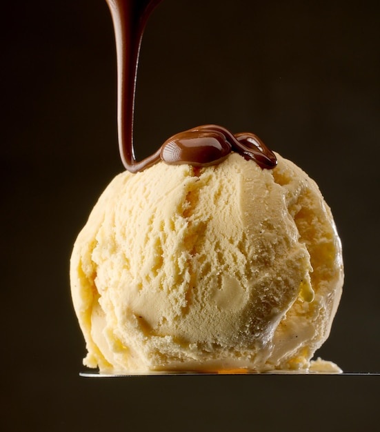 Melted chocolate pouring on vanilla ice cream