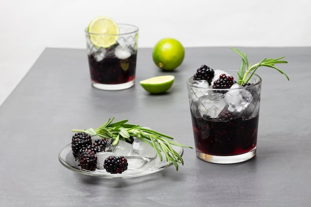 Melted ice spring of rosemary and blackberries on saucer Infused summer cold drink with blackberry ice and rosemary