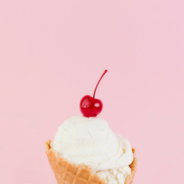 Melting ice cream ball with cherry above in cone