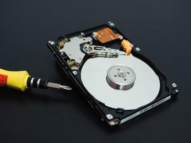 Memory repair concept Repair of storage systems Hard disk repair Hard disk with screwdriver on dark background