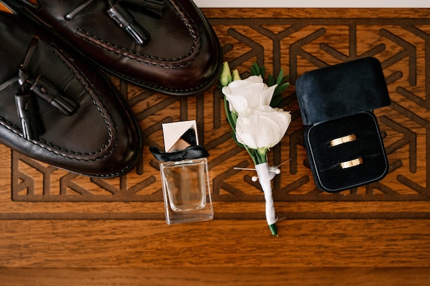 Men black leather shoes boutonniere and wedding rings in a box stand on a wooden carved table