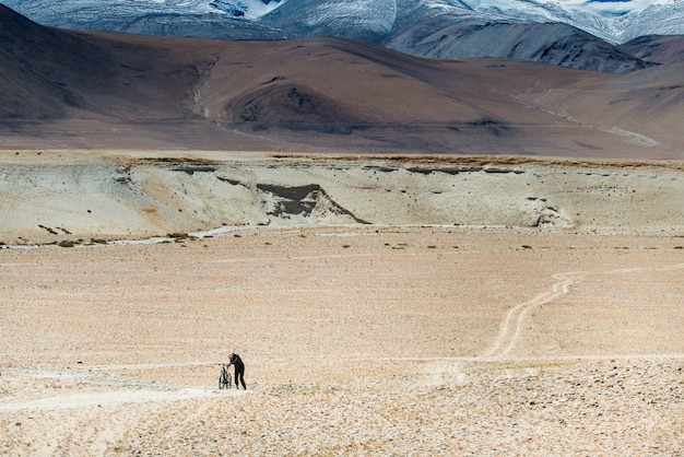 Men cyclists holding his broken bicycle through rugged road in Himalayas mountain range