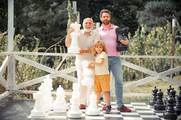 Men generation grandfather father and son playing chess Developing chess strategy Men in different ages playing chess board game Weekend family play