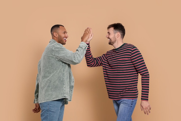 Men giving high five on beige background