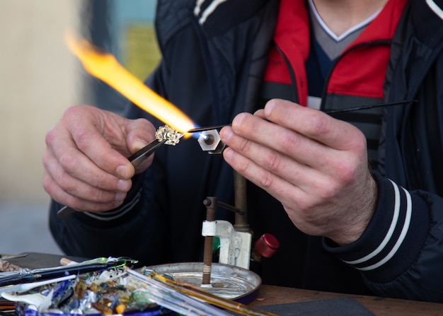 Men glassblower make handmade products  under gas burner.