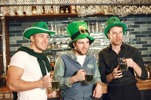 Men in green hats. Friends celebrate St. Patrick's Day. Celebration in a pub.