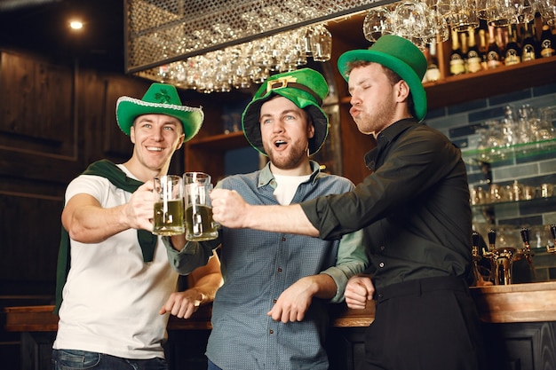 Men in green hats. Friends celebrate St. Patrick's Day. Celebration in a pub.