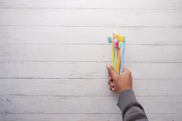 Men holding many colorful toothbrushes i