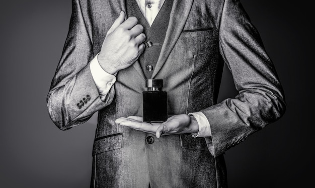 Men perfume in the hand on suit background Fragrance smell Black and white