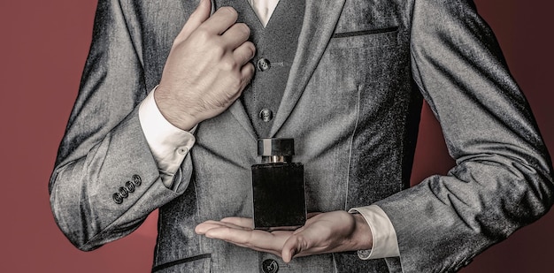 Men perfume in the hand on suit background Man in formal suit bottle of perfume closeup