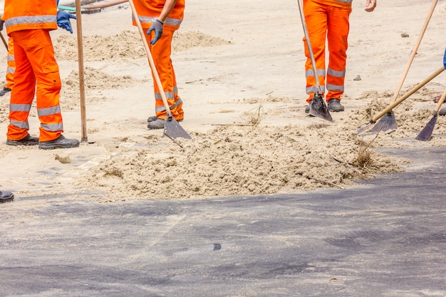 Men removing sand from the boardwalk after the hangover