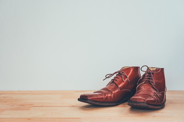 Men's brown shoes on a wooden floor.