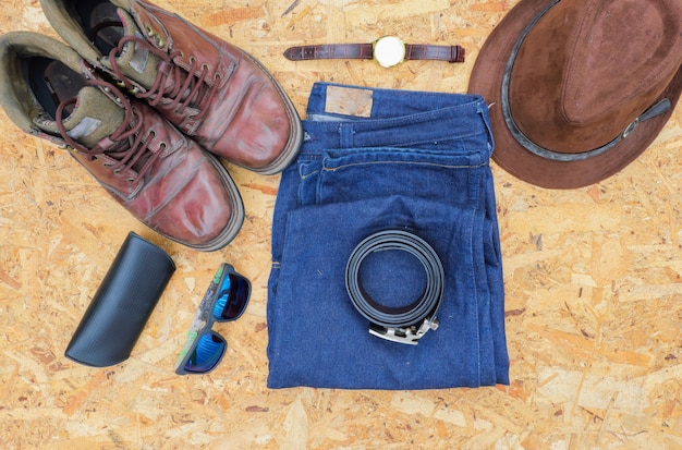 Men's casual outfits with leather accessories on wooden background, fashion concept.