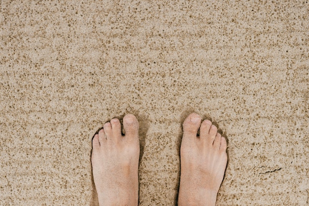 Men's feet on light sand background