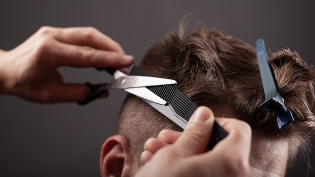 Men's haircut. master cuts man with scissors close-up.