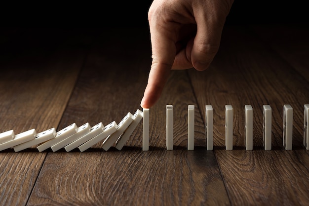 Men's hand stopped domino effect, on a brown wood