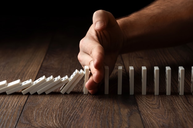 Men's hand stopped domino effect, on a brown wood