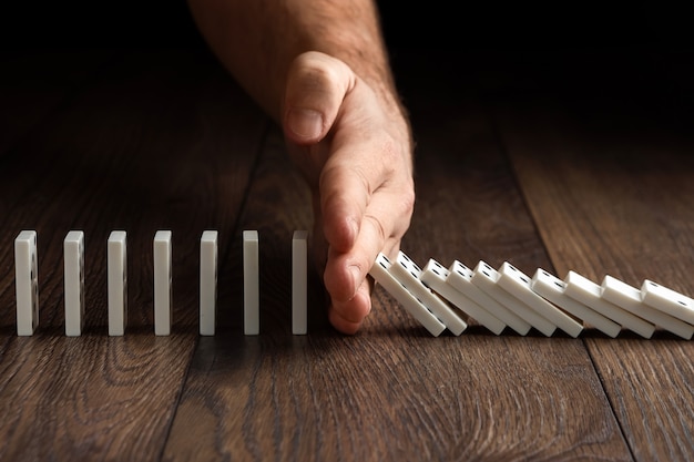 Men's hand stopped domino effect, on a brown wood