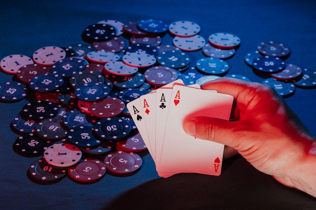 Men's hands hold cards on the background of playing poker chips