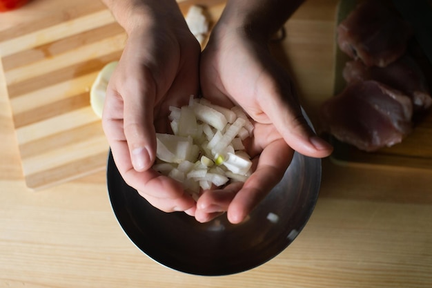 Men's hands hold pieces of onion near the bowl