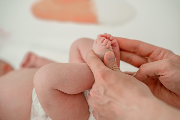 Men's hands hold the small legs of a newborn baby