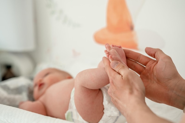 Men's hands hold the small legs of a newborn baby