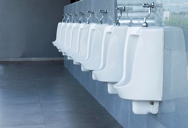 Men's room with white porcelain urinals in line in gas station