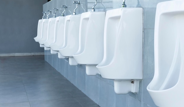 Men's room with white porcelain urinals in line in gas station