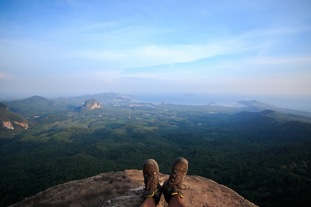 Men's shoes on the cliff There is a view below the forest.