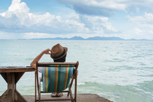 Men sitting on beach chair while using mobile phone, Copy space.