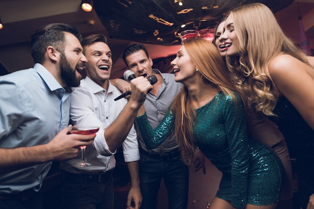 Men and women in the club sing together.